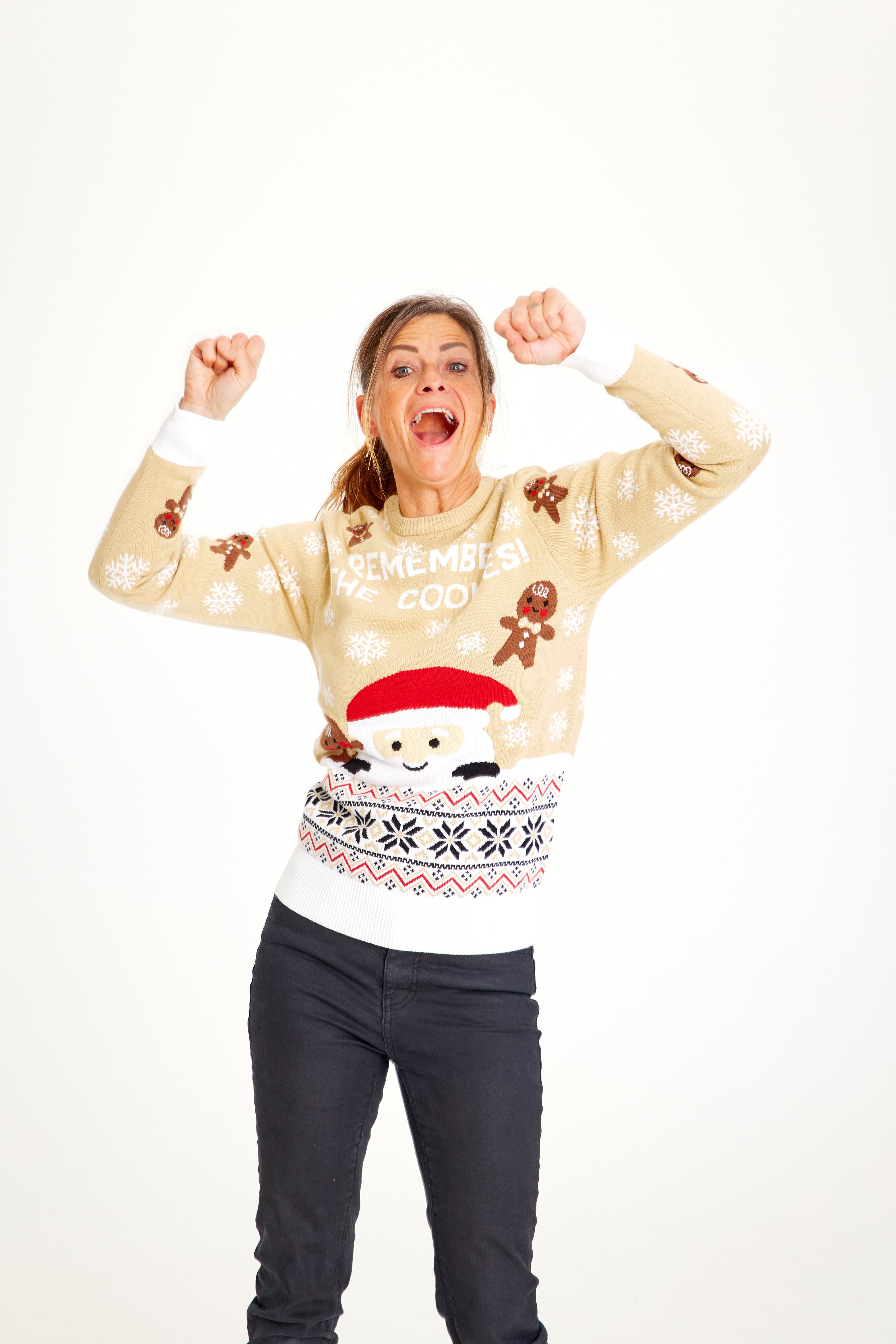 En dame med hænderne i vejret iført en julesweater.
